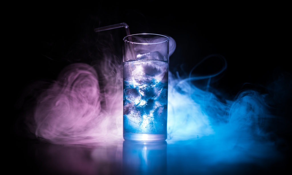 Clear glass of vodka with purple and blue fog around it