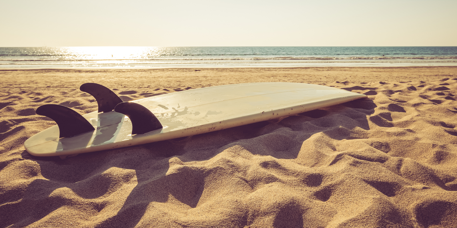 Surf board on beach at sunset